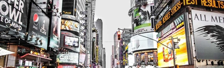 Billboards and digital advertising screens on a busy city street.