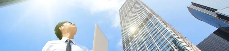 Aspiring project manager looking up at skyscrapers with a blueprint in hand, symbolizing career ambition in construction.