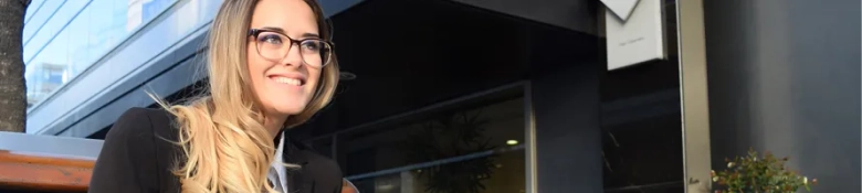 Smiling woman in business attire standing outside an office building.