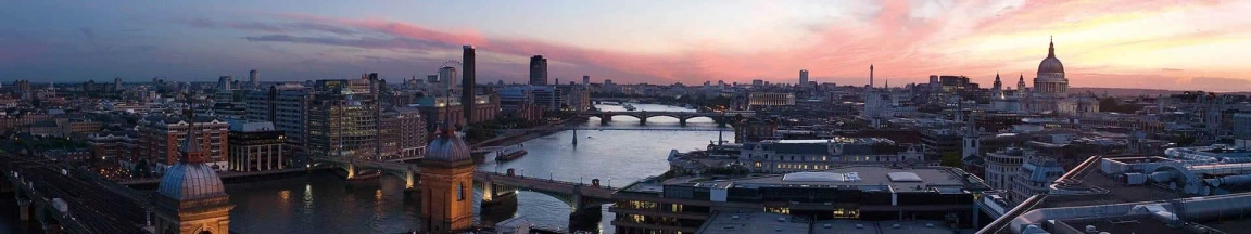 Panoramic view of London skyline at dusk with River Thames and St. Paul's Cathedral visible.