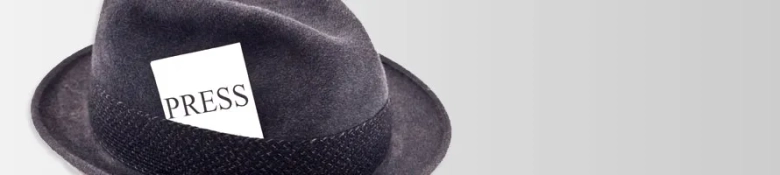 Black fedora with a white "PRESS" card tucked into the hatband.