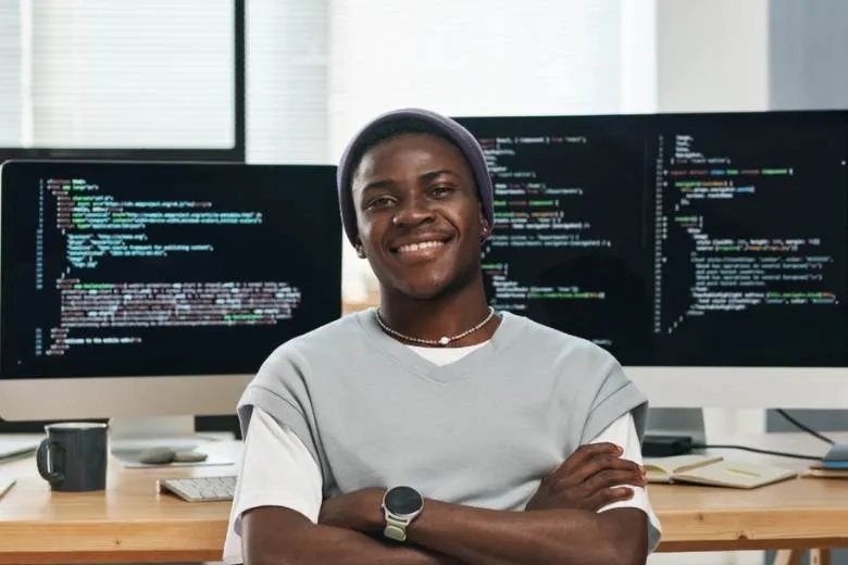 a man in front of computer screens smiling 