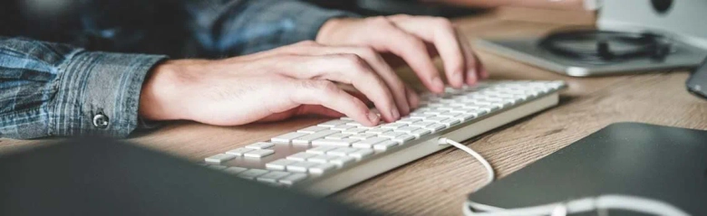 A pair of hand typing on a keyboard.