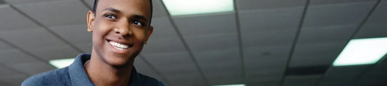 Smiling young man in an office environment looking confident and optimistic.