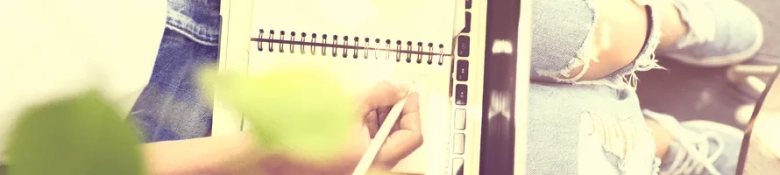 A notepad on a denim-clad lap