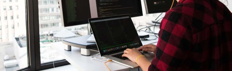 The picture shows a multimedia programmer working at a laptop