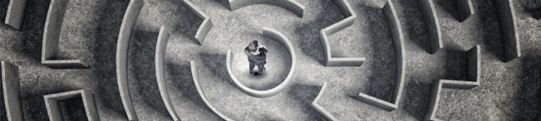Picture shows a graduate standing in the middle of a stone maze, signifying the decisions over a first graduate job