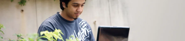 A male student browsing on a laptop: find careers information for international students here.