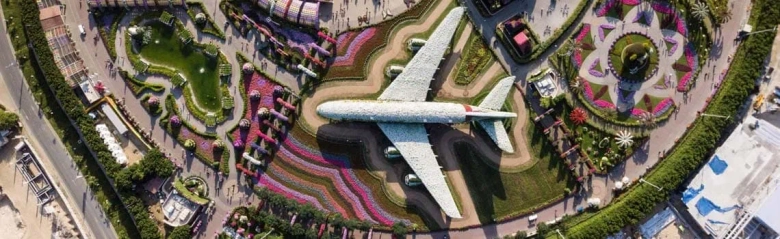 Aerial view of a park with a decorative airplane sculpture and colorful floral arrangements.