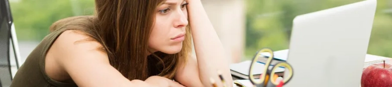 A graduate looking at her computer screen in frustration. 