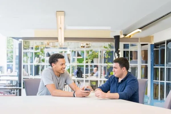 Two men sat talking at a table 