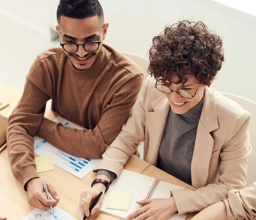 Two apprentices around a table, with business papers on it, dressed in smart casual workwear