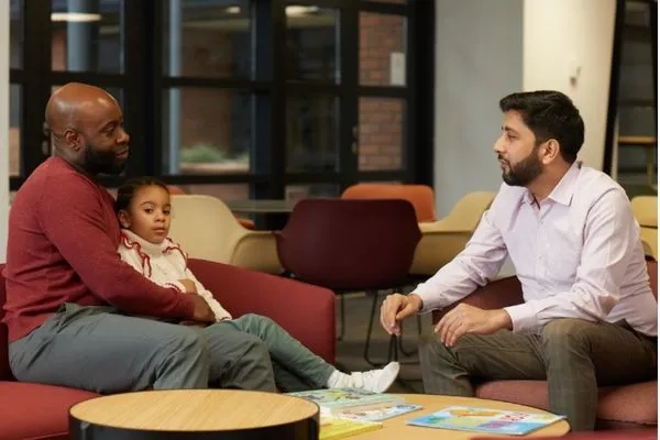 A social worker talking to a man and child 