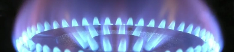 A lighted gas hob. The flame is a light-blue colour. 