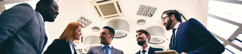 Group of professionals in business attire engaged in a discussion under ceiling lights.