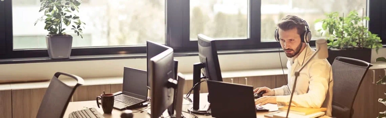 A male civil Service administrator sat at his desk using a computer. 