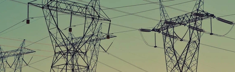 Electricity pylons and power lines against a twilight sky.