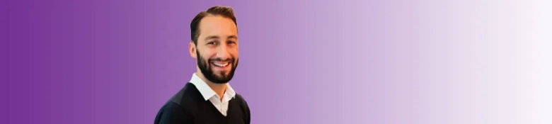 Smiling young man in business attire with a purple gradient background.