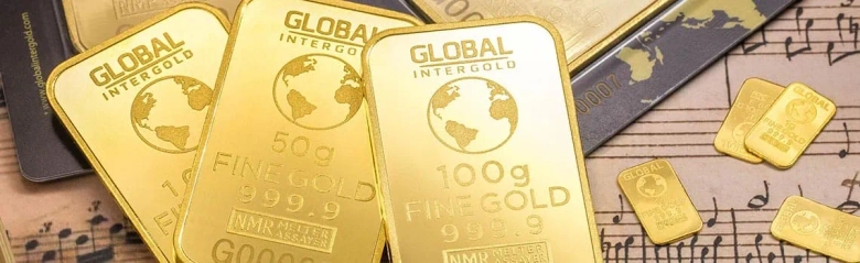 Gold bars of various sizes labeled with "Fine Gold 999.9" and "Global Intergold" on a background with financial documents.