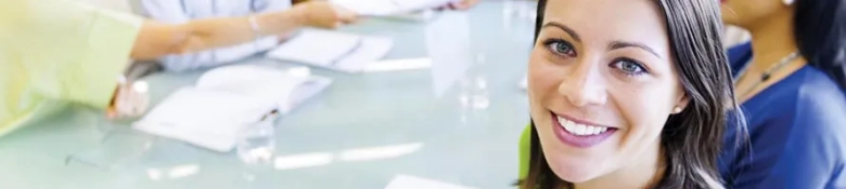 Smiling woman in a training session with colleagues around a table.