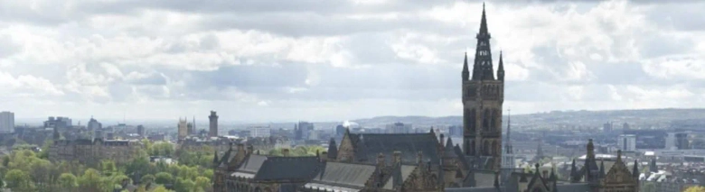 Panoramic view of the University of Glasgow with the iconic tower, surrounded by cityscape and cloudy skies.