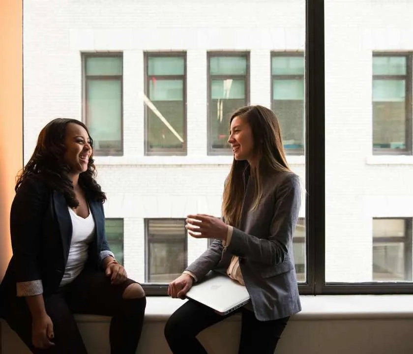 Two people chatting against an office building window