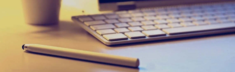 Close-up of a pen next to a keyboard on a desk, symbolizing media analysis work.