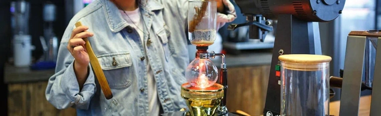 Food technologist monitoring the process of coffee brewing using a siphon coffee maker.