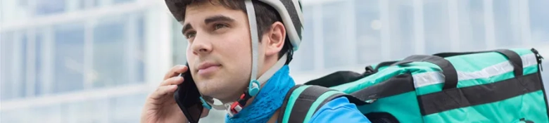 Delivery person with helmet talking on the phone while carrying a large insulated backpack.