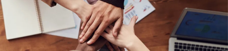 A group of people putting their hands together signifying collaboration and teamwork. 