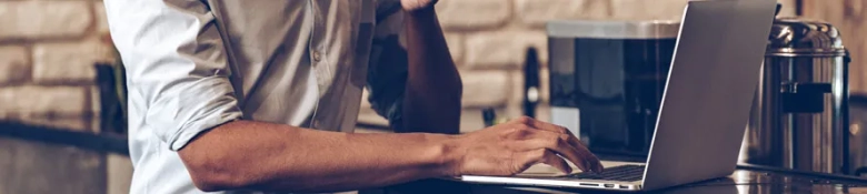 A person using a laptop sitting at a counter. 