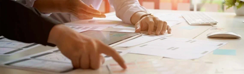 Two professionals collaborating over documents with digital tablet on a desk.