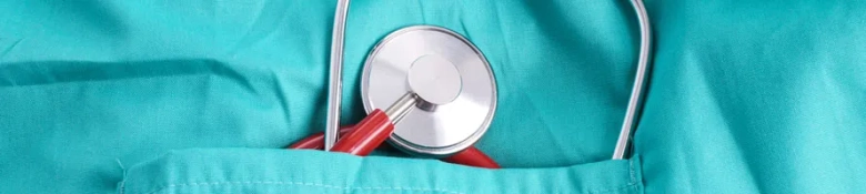 Close-up of a stethoscope in the pocket of a teal nurse's uniform.