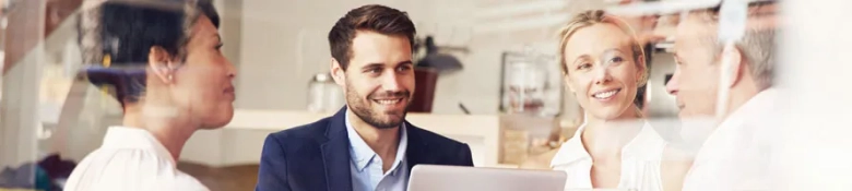 Professionals engaging in conversation at a networking event with one man using a laptop.