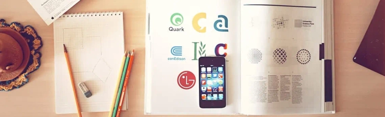 The picture shows an iPhone, sketchpad and design textbook, highlighting the graphic design skills needed for a job. 