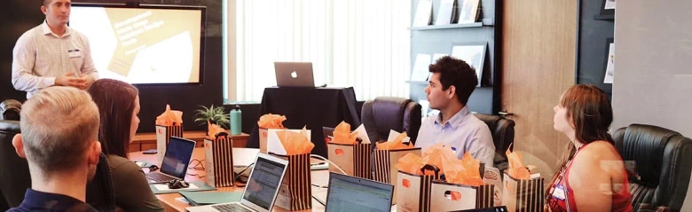 Four young people sitting around a boardroom table with laptops: social media manager job description