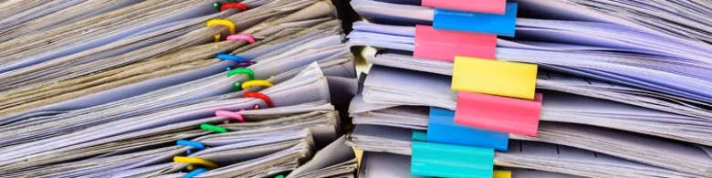 Stacks of documents with colorful tabs indicating organization for management accounting work.