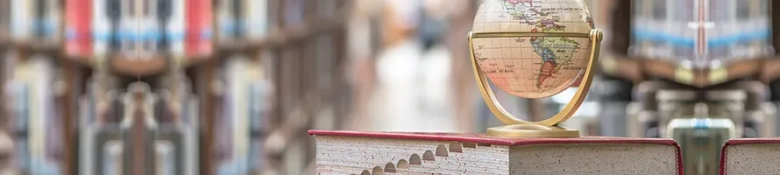 A globe ornament placed on top of a book in a library